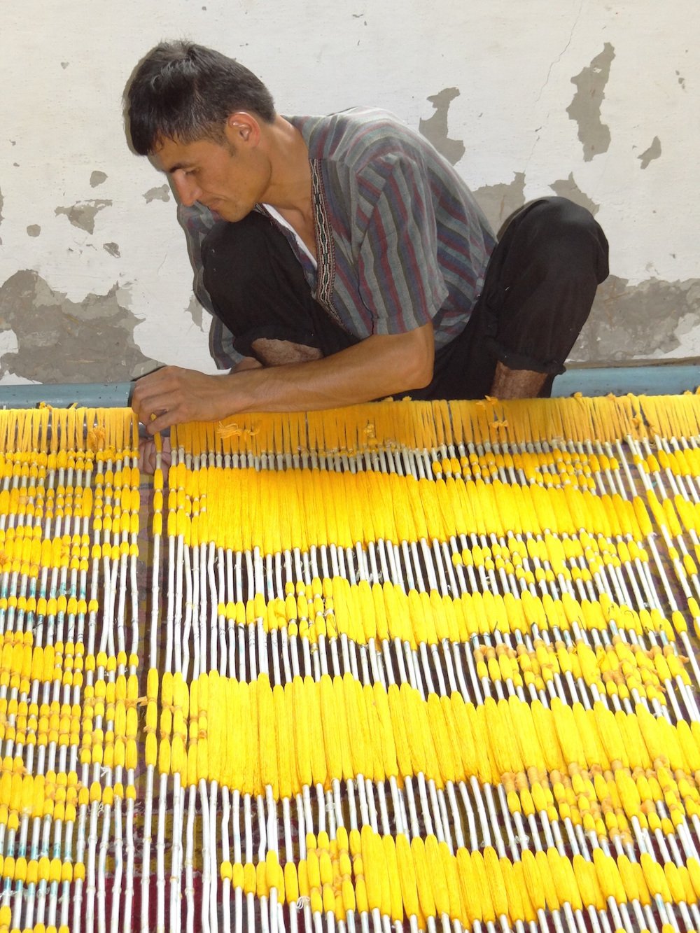 Man threading yellow silk at Yodgorlik factory. Image: Adam Jones under a CC licence 