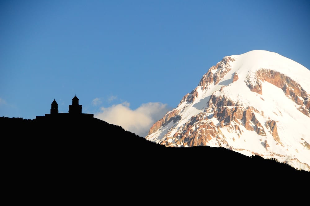 The Trinity Church above Stepantsminda, with Mount Kazbek in the background. Image: Panegyrics of Granovetter under a CC licence