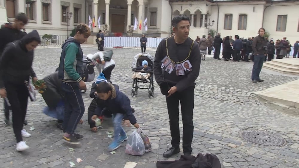 Alexandru Solomon throws money to the ground outside the Bucharest Orthodox Cathedral as part of his performance-protest