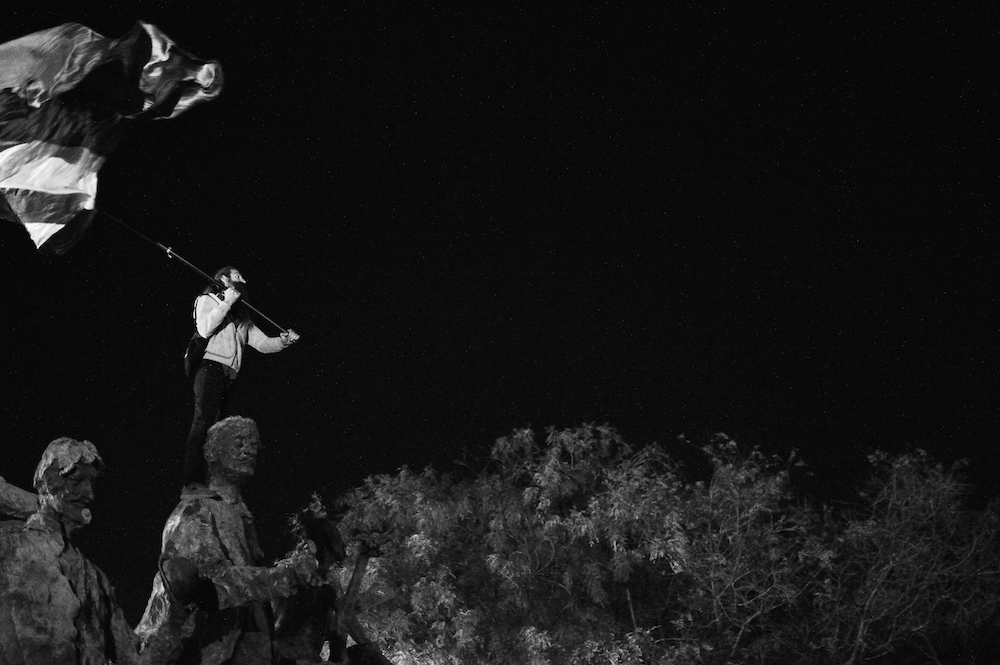 A protester scales a monument in Bucharest (image: J. Stimp under a CC licence)