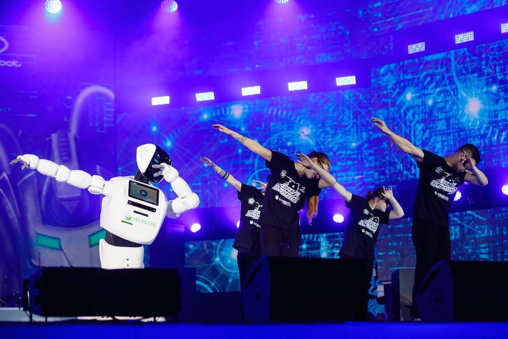 Dancers “dab” with a robot branded with the Sberbank logo — a far cry from the Festival’s communist origins. Image: World Festival of Youth and Students 2017/Facebook