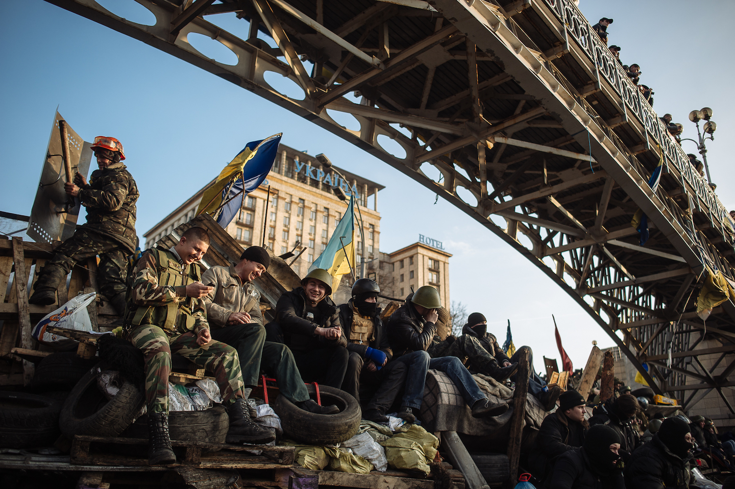 Protesters sit on a barricade under Millennium Bridge in Kyiv