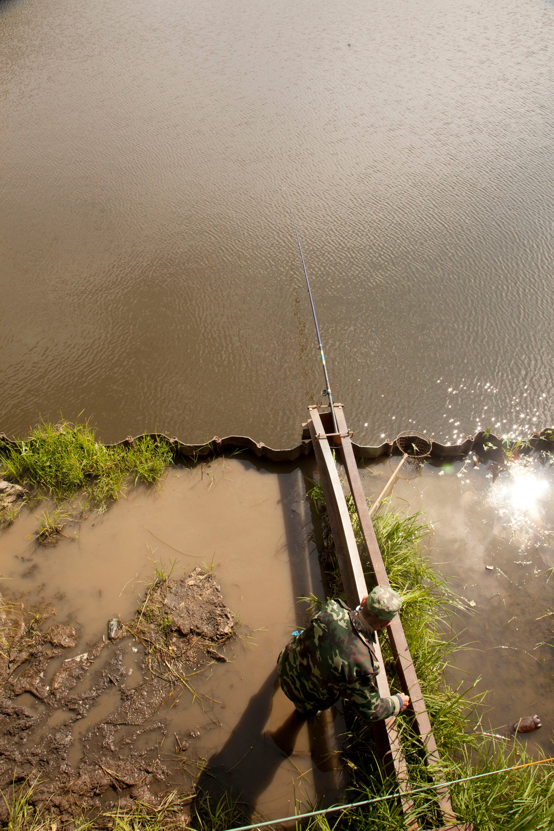 A man sets up his fishing pole under a bridge in town