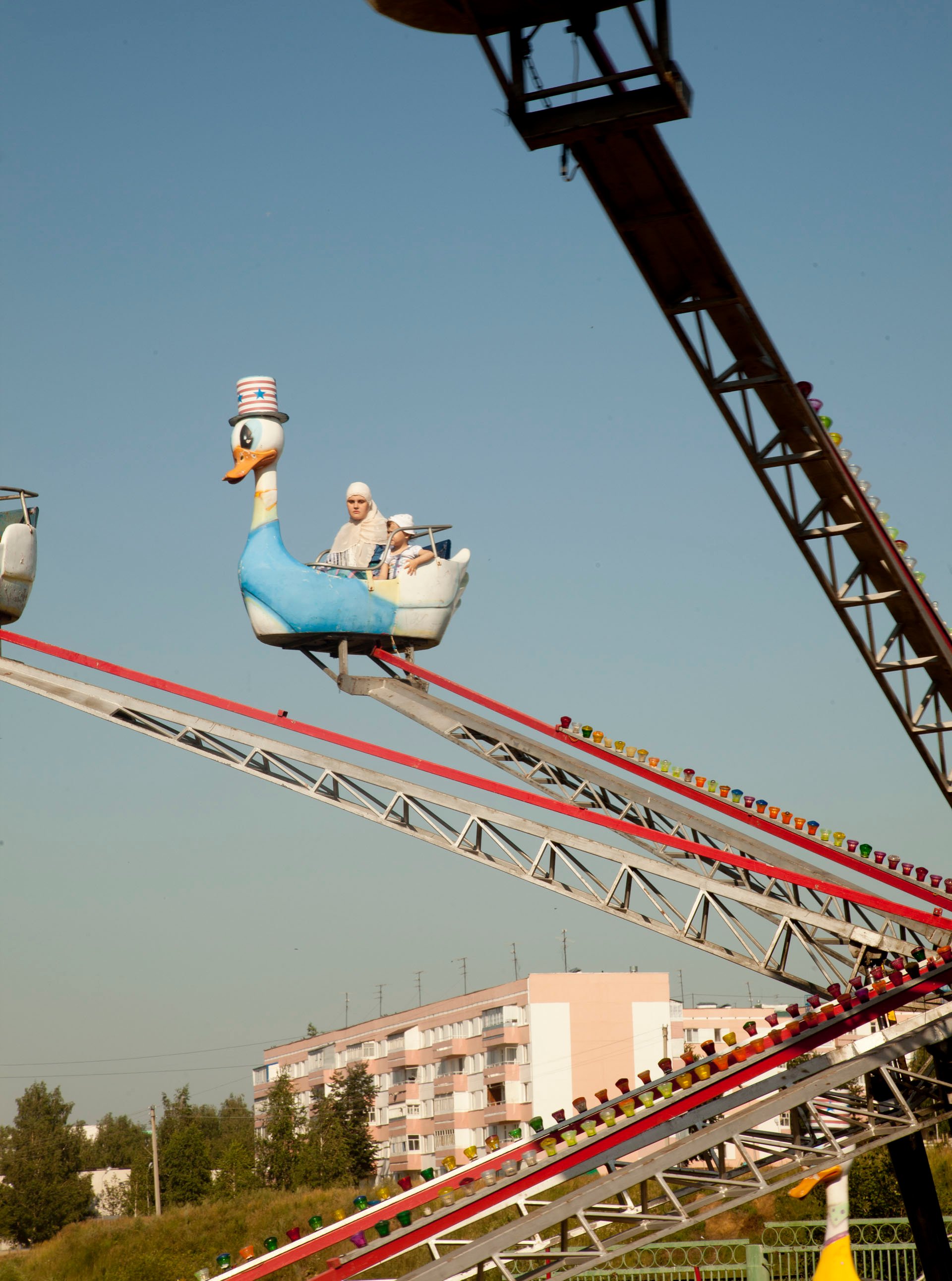 A woman and child are the only two on a carnival ride in Kamskie-Polyani