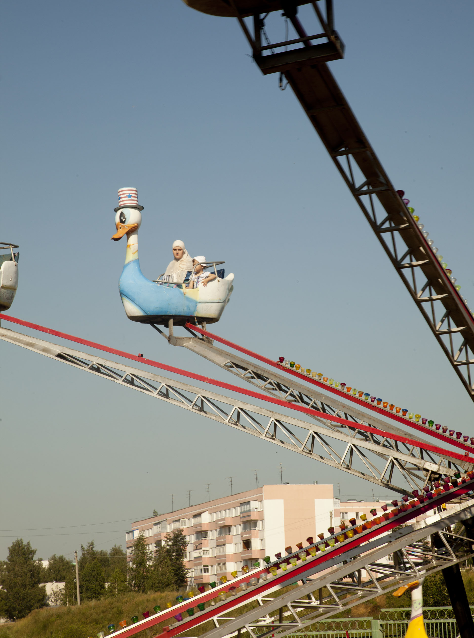 A woman and child are the only two on a carnival ride in Kamskie-Polyani