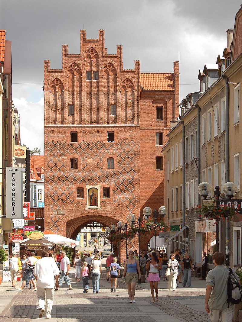 Pedestrians walk under Olsztyn's old city gate. Image: Nol Aders/Wikimedia Commons under a CC licence