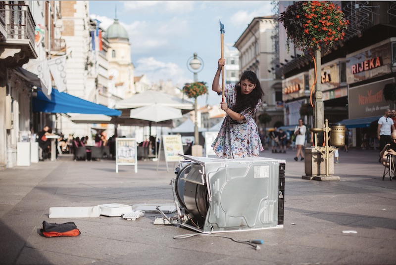 Selman destroys a washing machine during a performance. Image courtesy of the artist