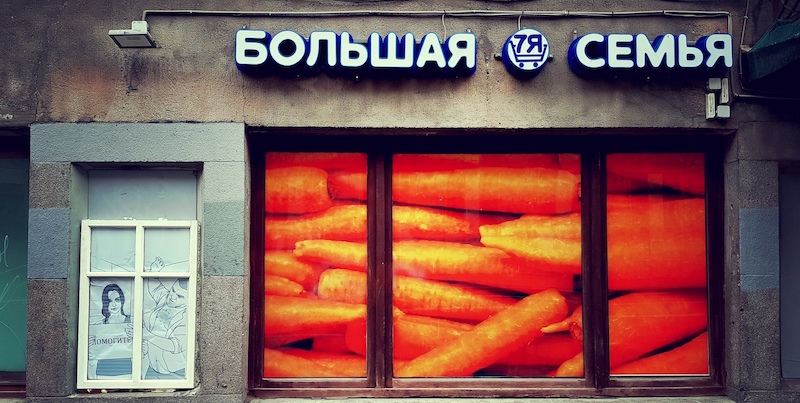 An artwork against domestic violence outside a shop called 'Big Family'. The woman is holding a sign which reads 'HELP'.