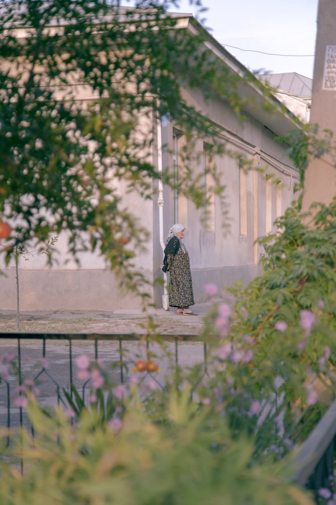 An elderly woman waits on a street corner in Tashkent. Image: Kamila Rustambekova