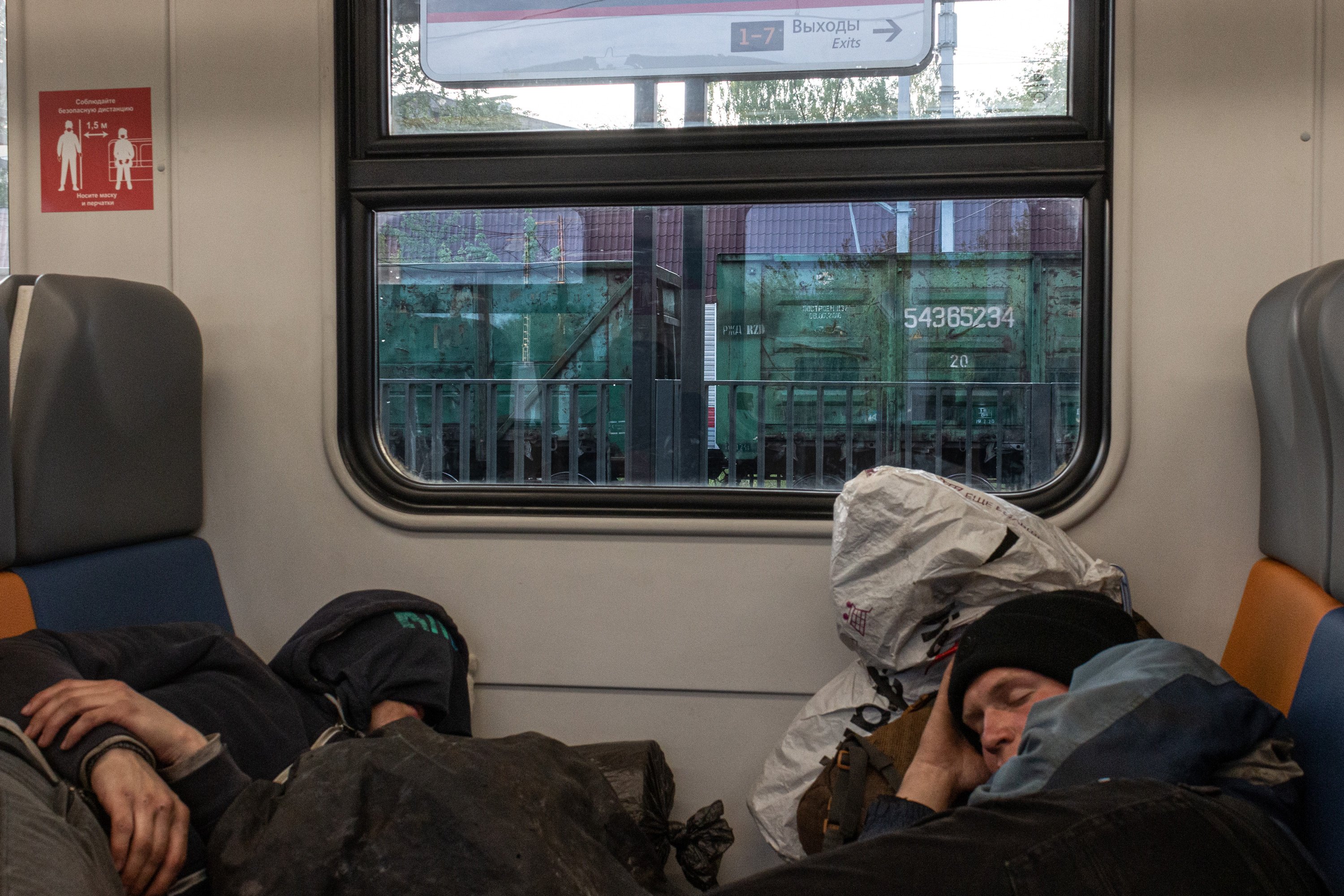 Vlad and Vanya sleeping in a suburban train heading to Moscow. There is a freight train from an unknown marshalling yard outside the window.