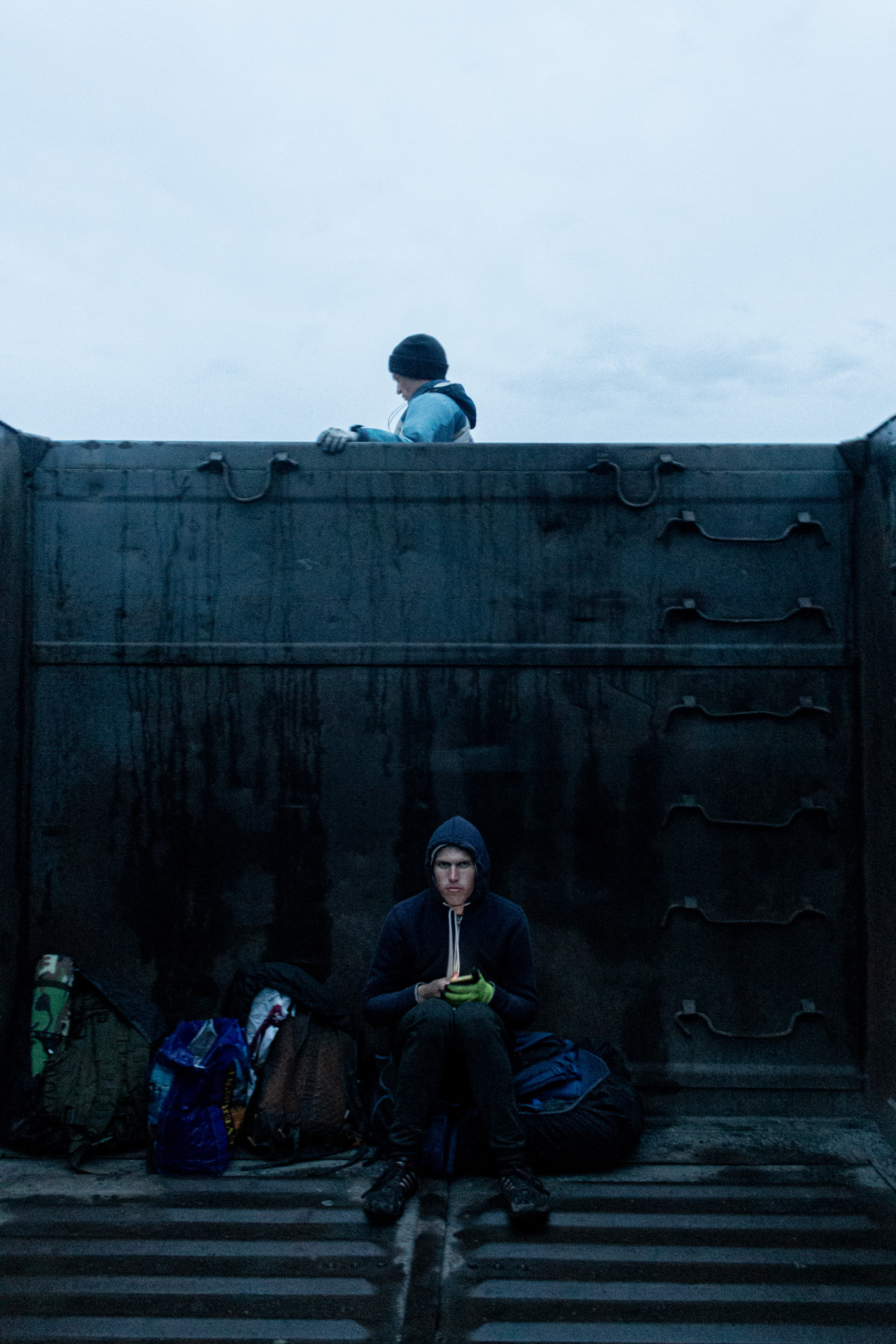 Vlad is busy with his phone while Vanya is admiring the landscape from in between the wagons.