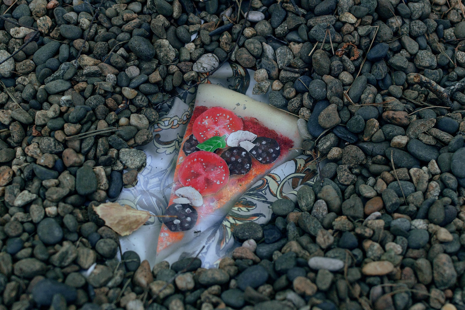 Sekretik in the form of a pizza made of fabric and foam rubber in pebble stones under glass. Created by the girls creative cooperative Businki, 2020. Sekretiki (“little secrets”) is a children’s game, where small objects are covered with glass and buried